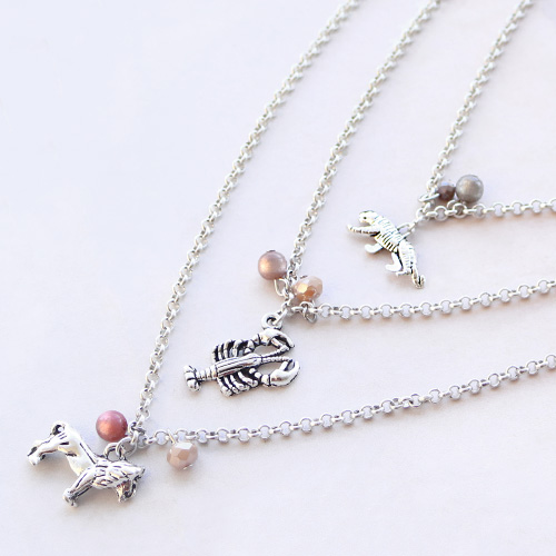 Bracelets &eacute;lastiques et colliers superpos&eacute;s avec des breloques en m&eacute;tal 